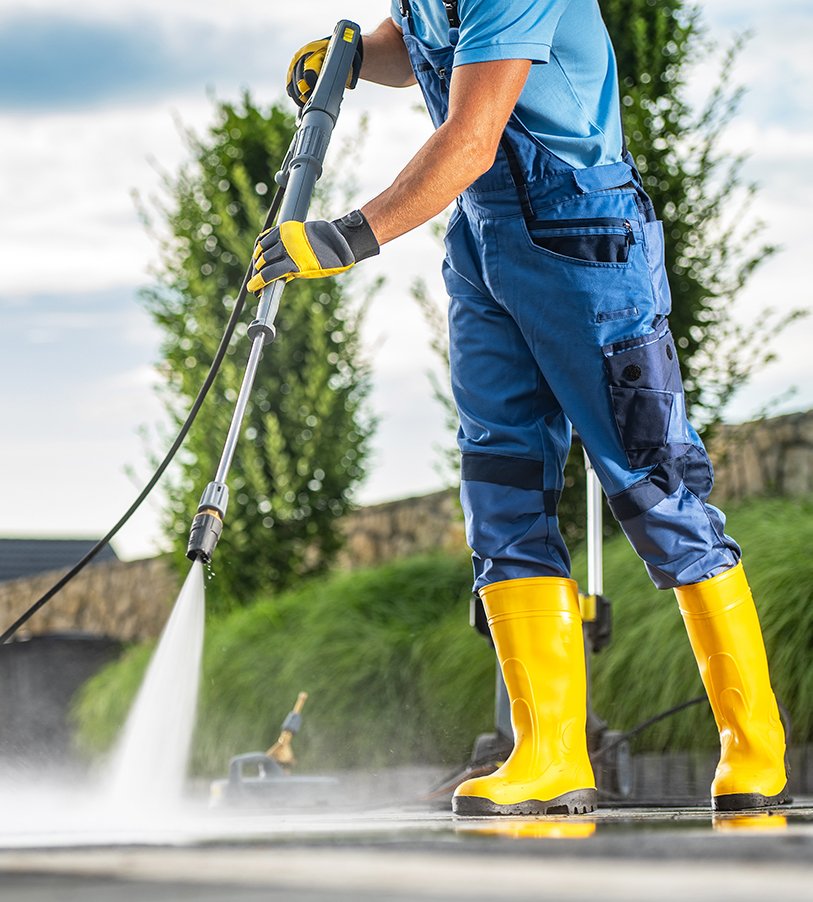 Caucasian Pressure Wash Staff Member Using Powerful Pressure Washer to Clean Dirty Driveway