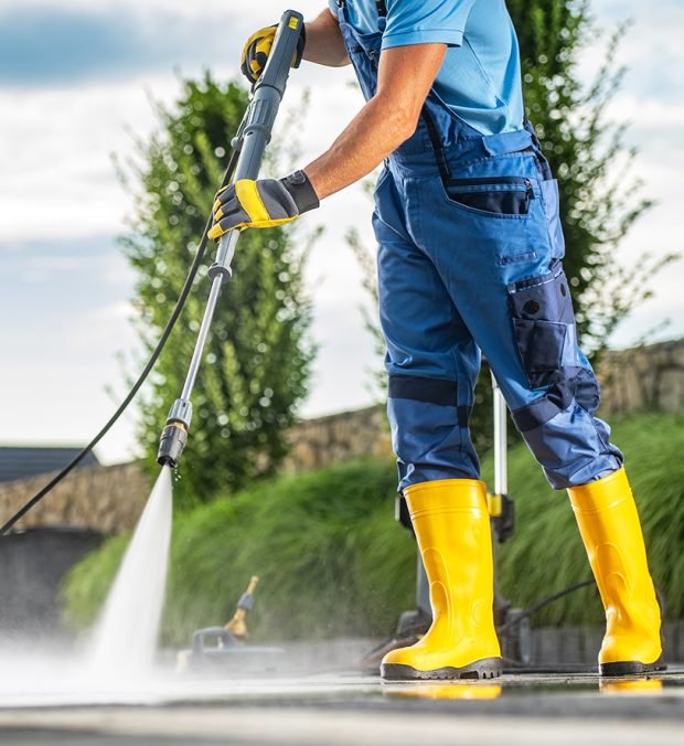 Caucasian Pressure Wash Staff Member Using Powerful Pressure Washer to Clean Dirty Driveway